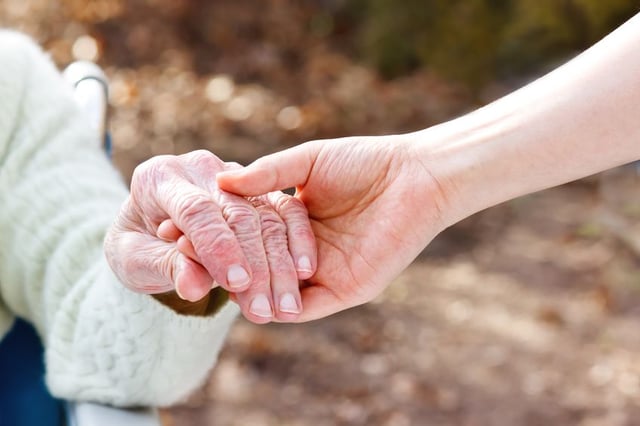 Senior and caregiver holding hands